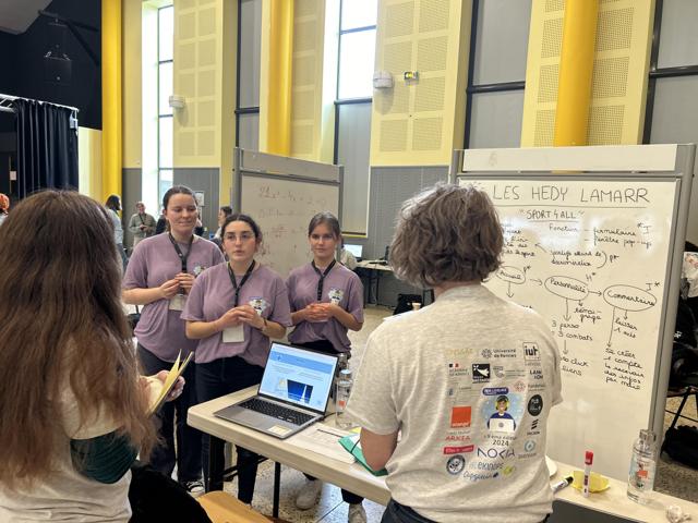 Une équipe présente son projet au jury, devant un tableau blanc couvert de notes